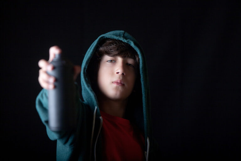 A young man in a hoodie is holding a spray paint can